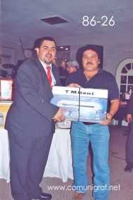 Foto 86-26 - Feliz agraciado con un reproductor de DVD, lo entrega Juan Elías Cordero (izq) en la tradicional Comida Baile del día del Impresor de Canagraf Guanajuato, realizada el 24 de Septiembre 2005 en el Hotel La Nueva Estancia de la Ciudad de León, Guanajuato México.
