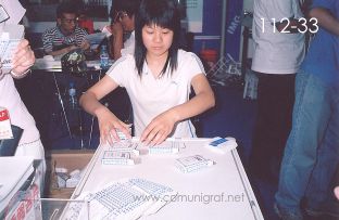 Foto 112-33 - Señorita de Shanghai Eterna Machinery Co. LTD armando y empacando cartas de naipes de poker las cuales las obsequiaba a los visitantes a su stand en la expo All In Print China en Shanghai China - 15-Junio-2006